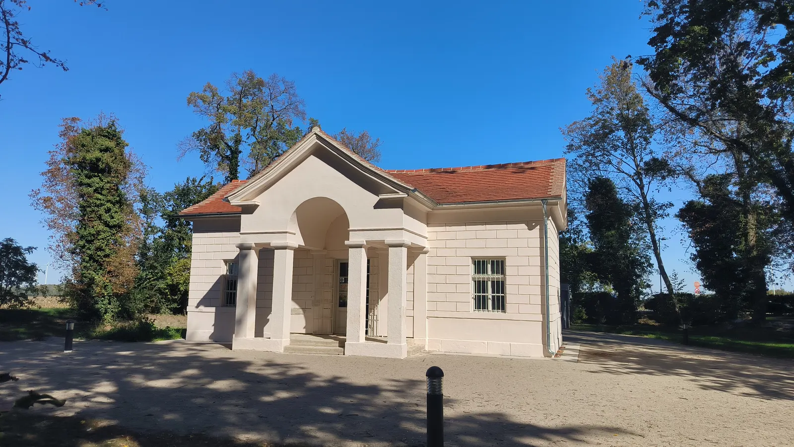 Das helle Wächterhaus im Schlosspark Pottendorf, umgeben von Bäumen